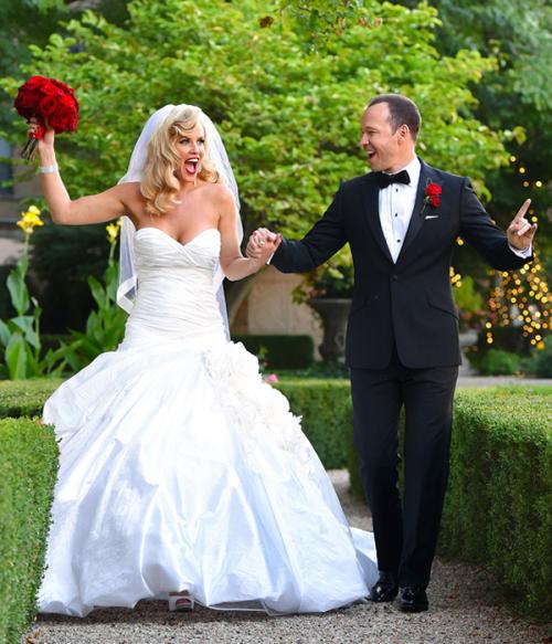 Невеста была в белом платье без бретелек с пышной юбкой от Ines Di Santo. Дополняла наряд длинная фата и букет из красных роз.