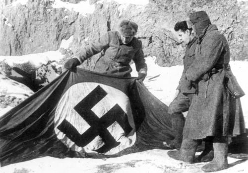 Советские бойцы рассматривают захваченный нацистский флаг на берегу Волги в Сталинграде.