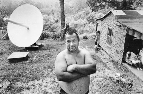 Берт Джетт  гордо стоит во дворе своего дома неподалёку от городка Блу Крик, Элквью, Западная Вирджиния, где он и его два брата установили спутниковую тарелку стоимостью 7800 долларов, чтобы улучшить прием ТВ сигнала (снимок сделан 14 июля 1981 г.).