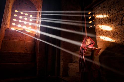 Источник светаМолодой монах нашел идеальный источник света, чтобы читать книгу внутри своей пагоды.
