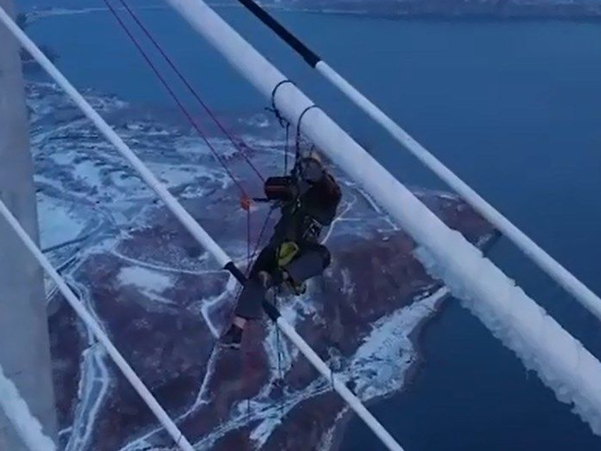 Альпинист чистит от льда мост на Русском