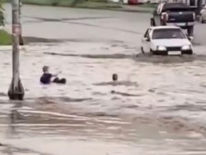 Суровые челябинские дети купаются в луже на дороге, катаясь на волнах