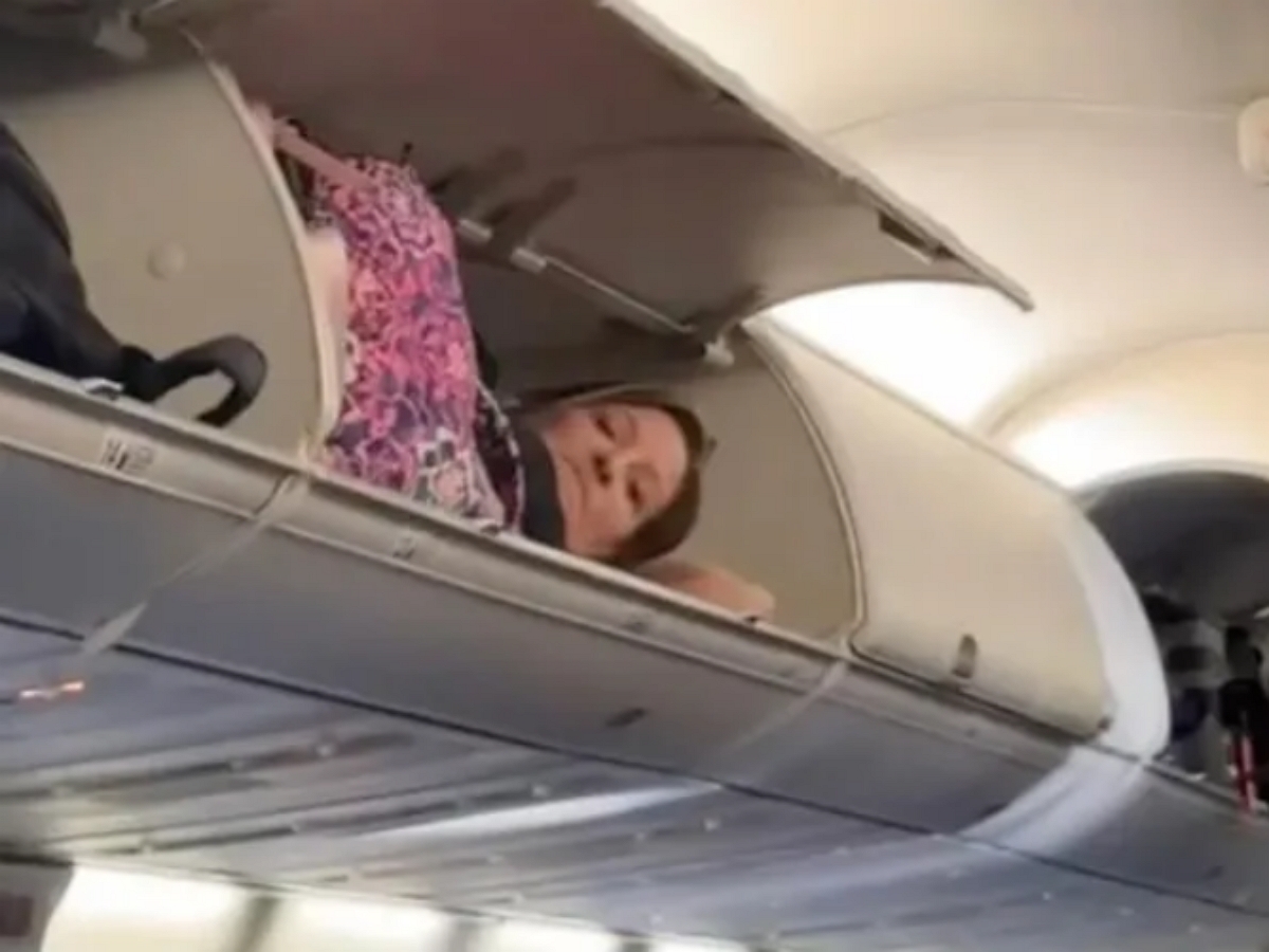 Женщина разлеглась на багажной полке в самолете
